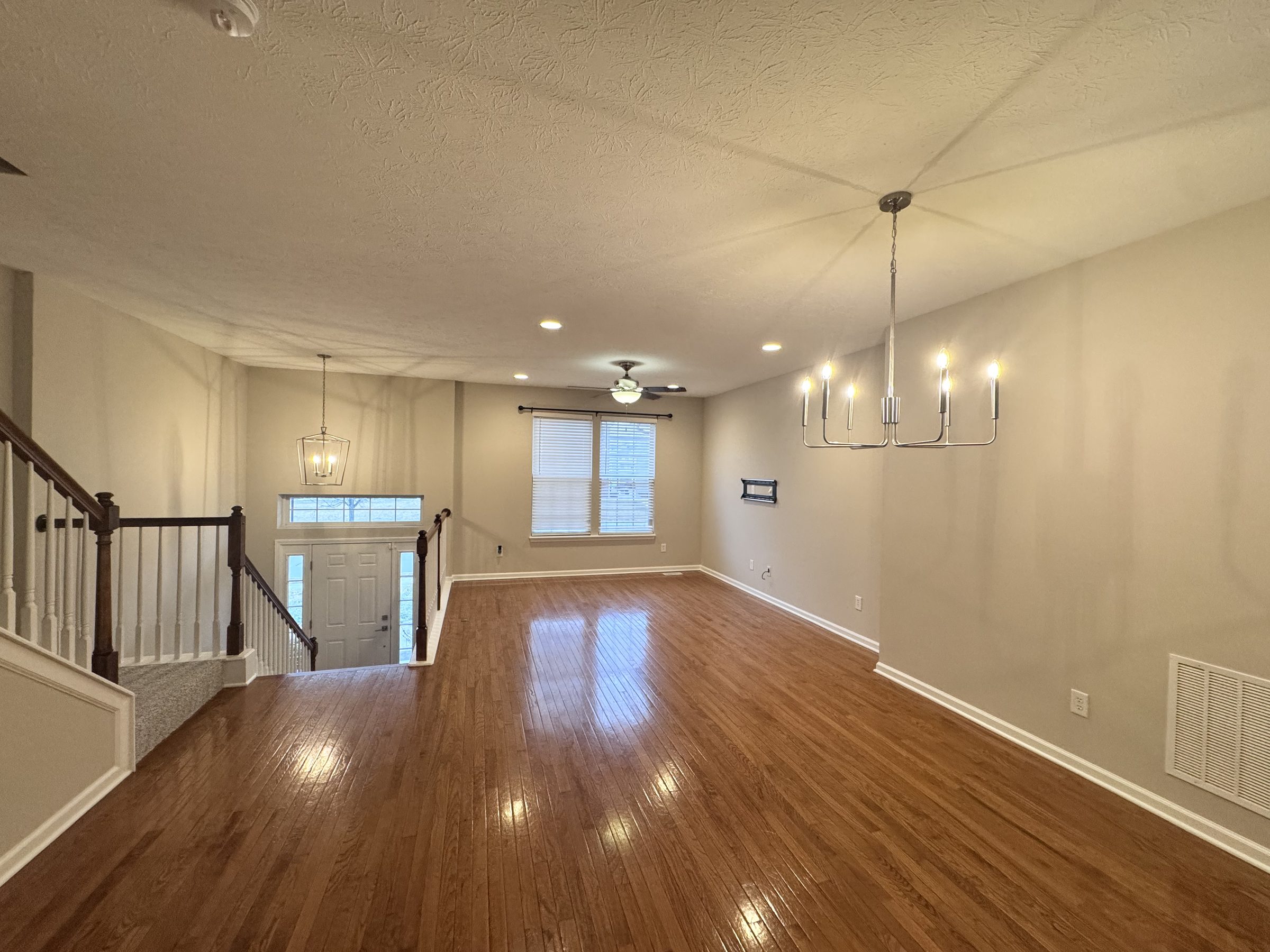 Freshly painted entry and living space with refinished hardwood floors and a new chandelier