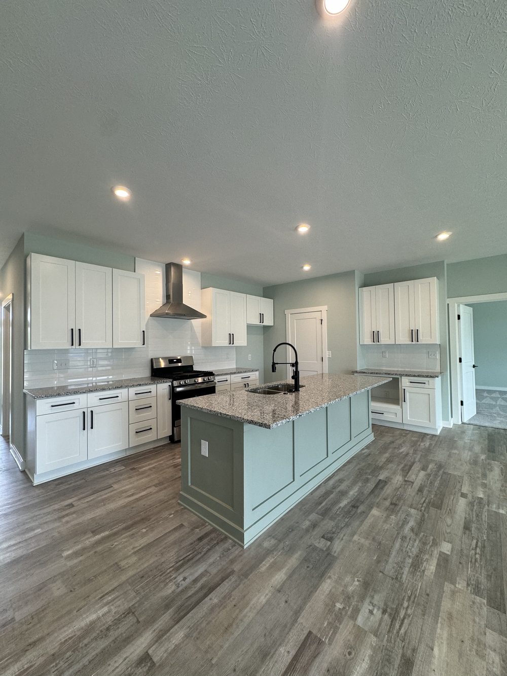 Refreshed kitchen with white cabinets, fresh paint, a tiled backsplash and new flooring