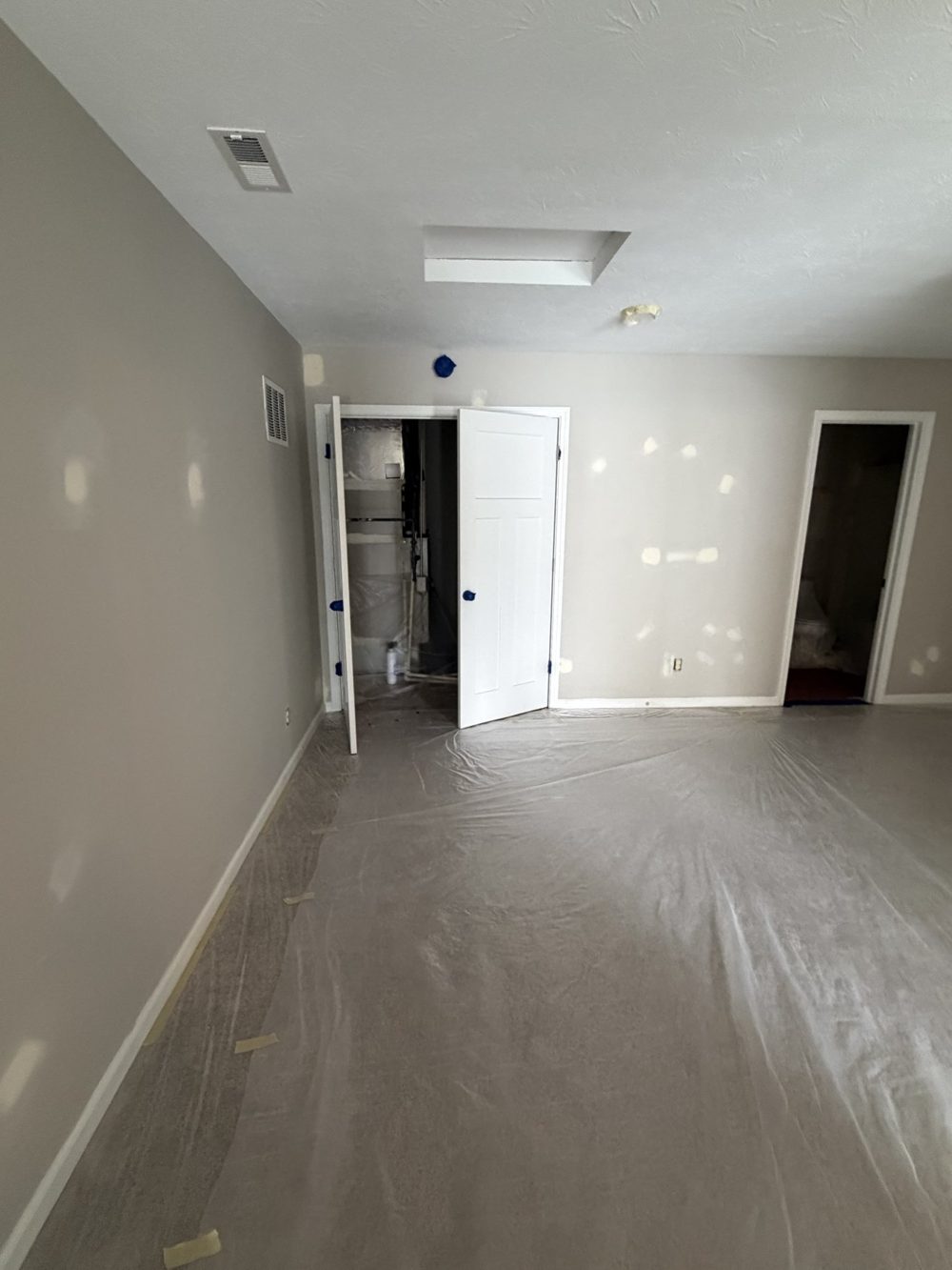 Hallway with patched walls and floors papered for painting