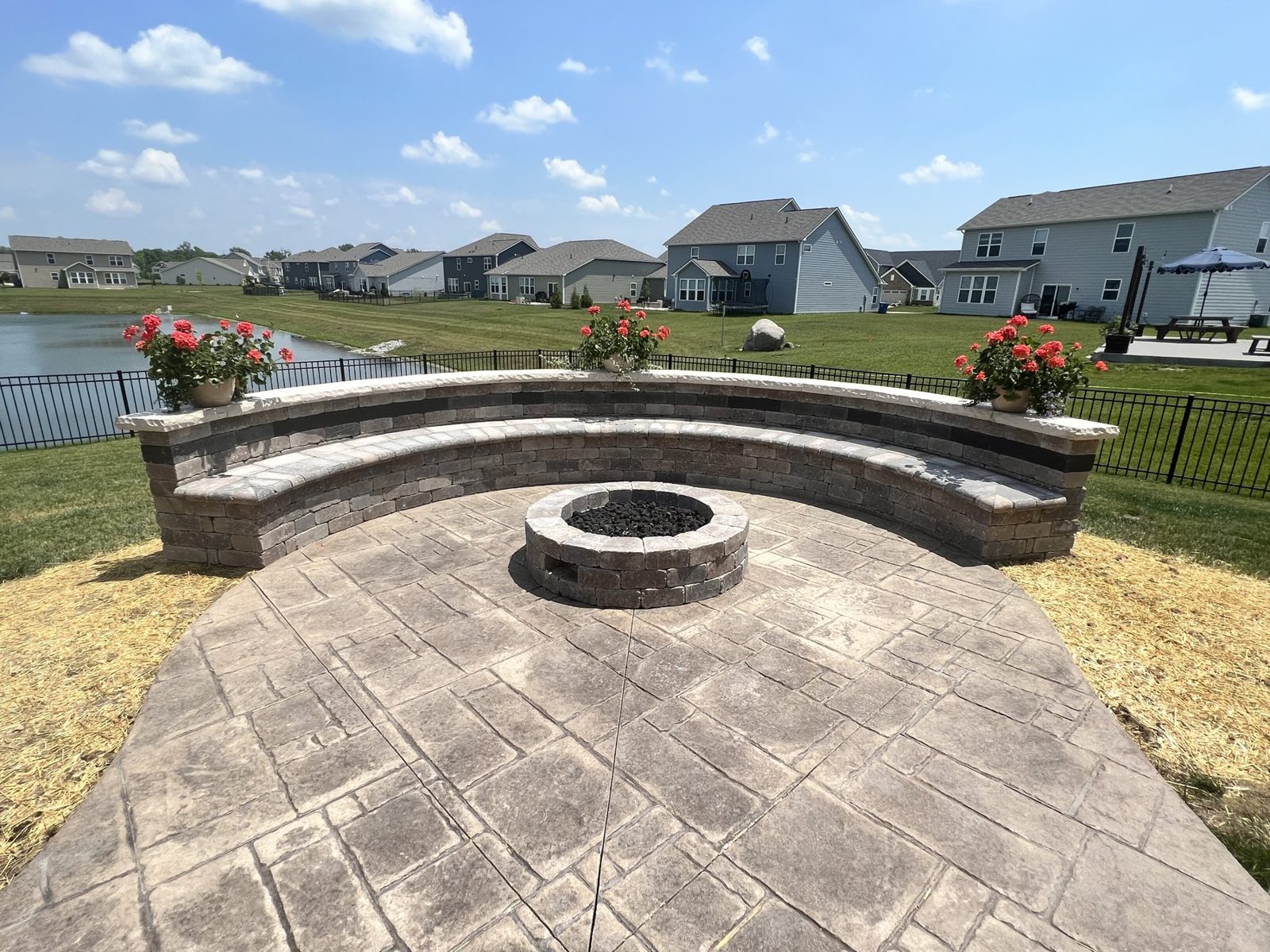 Curved stamped concrete patio with a round stone fire pit