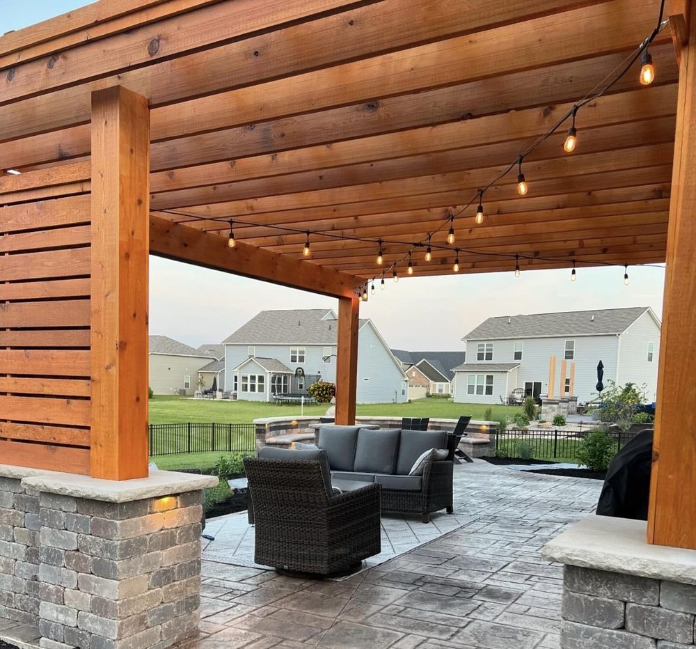 Cedar pergola with stone columns and string lights over a paver patio