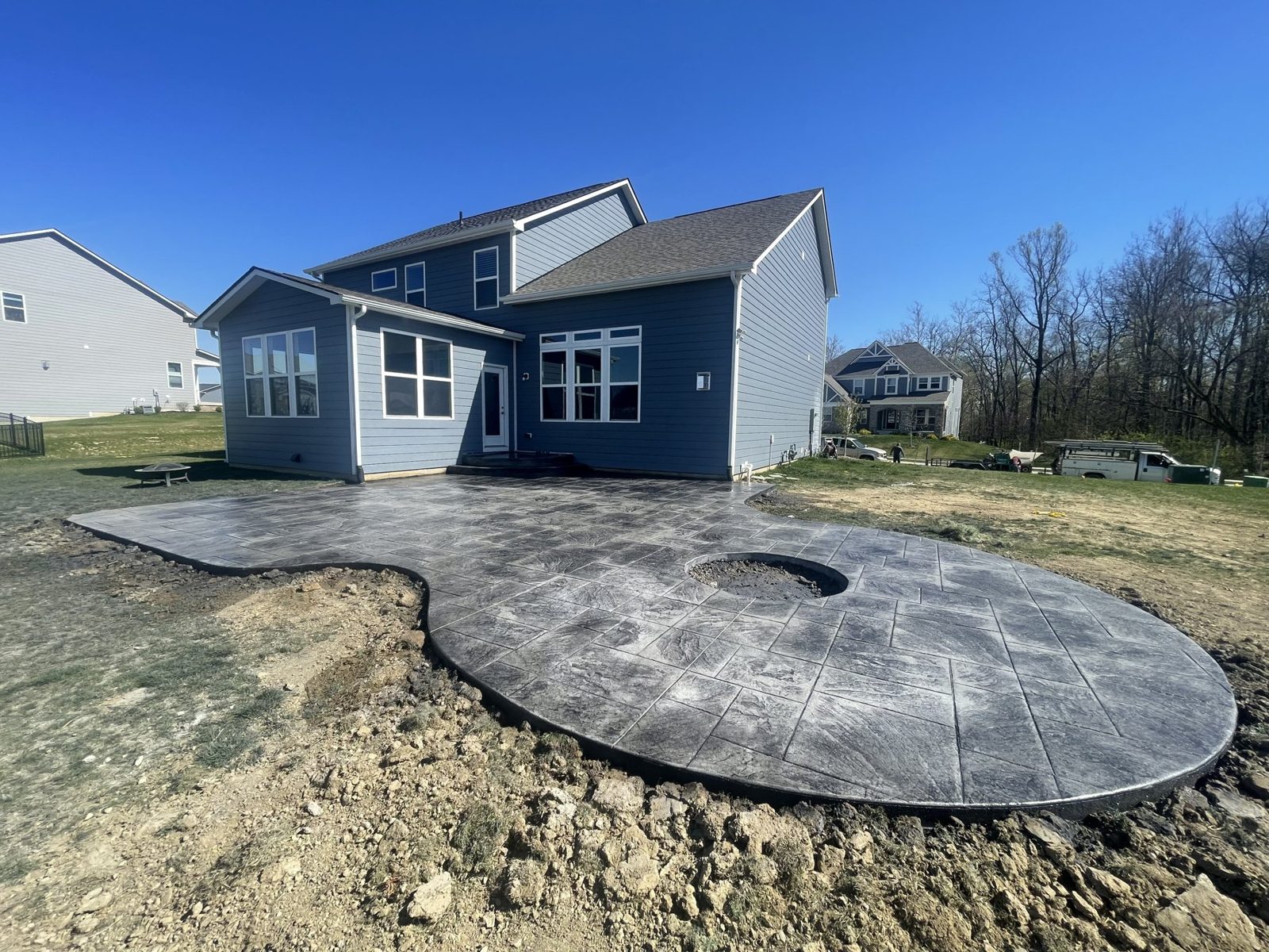 Round stamped concrete patio poured beside a two story home