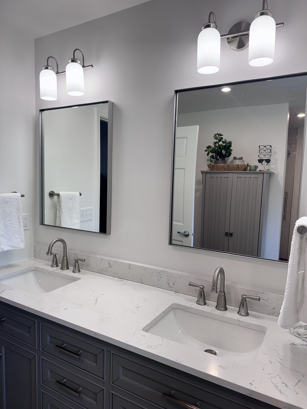 Double vanity with new mirrors, wall lights and faucets in a refreshed bathroom